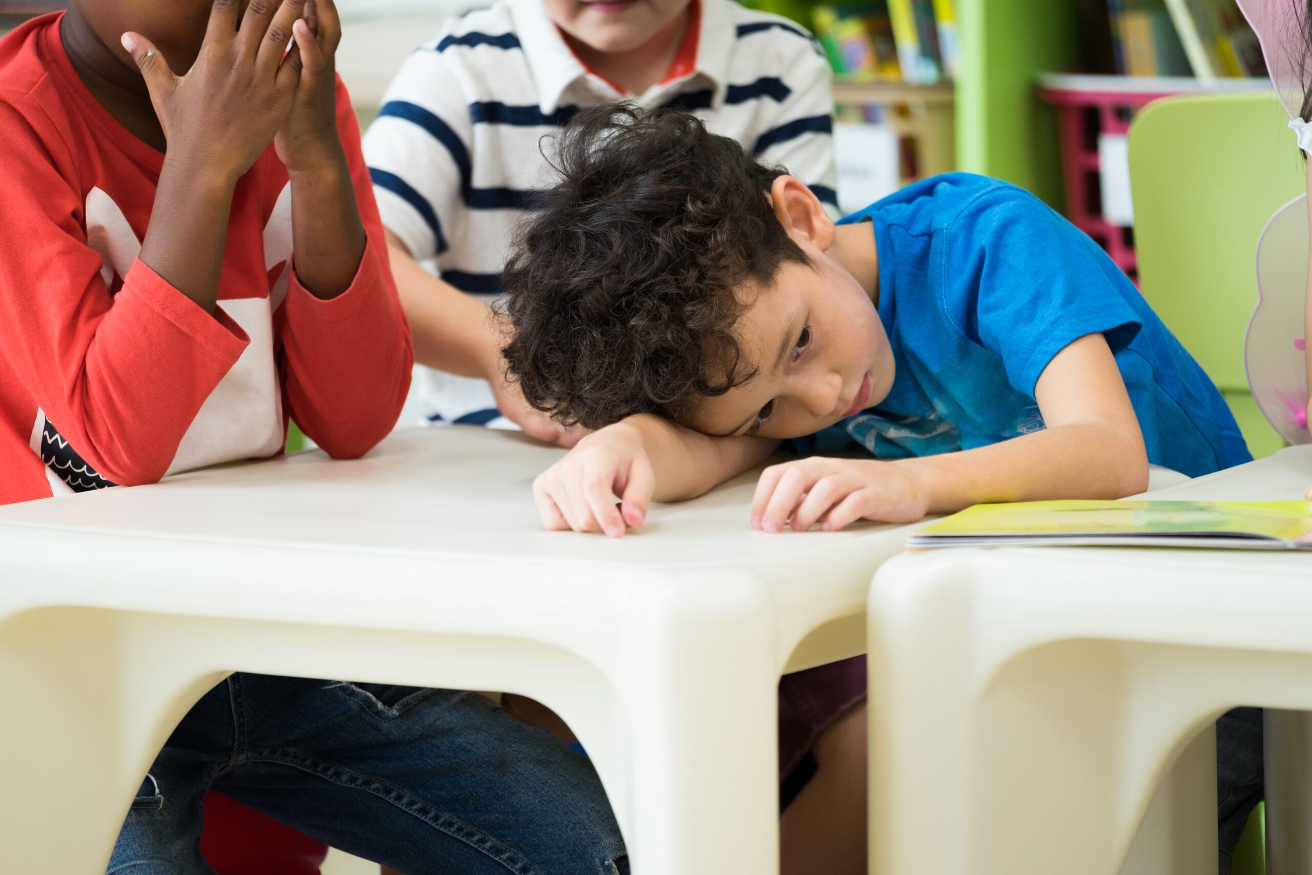 Child with sadness emotion sitting in classroom in kindergarten preschool